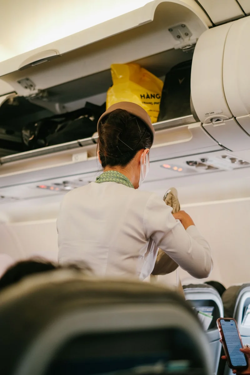 Cabin crew member assisting with luggage inside an aircraft