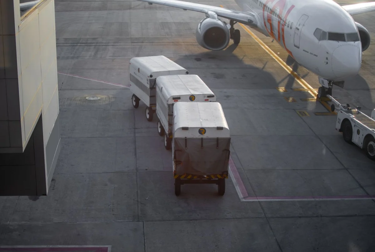 Aircraft at an airport gate beside cargo loading units